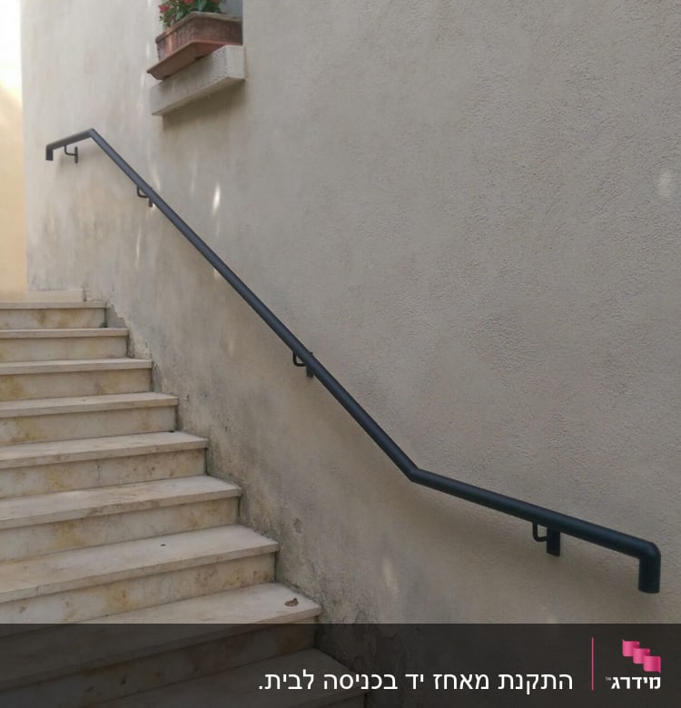 מעקה מתכת שחור על קיר מדרגות